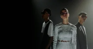 Three models wearing stylish outfits and sunglasses.