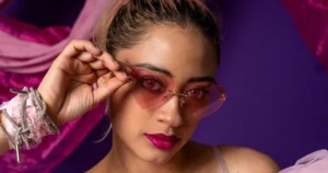 Person in heart-shaped pink glasses, vibrant background.