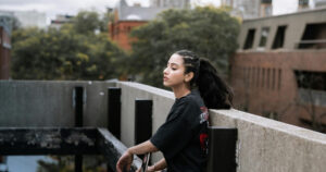 Woman posing thoughtfully on a concrete ledge.